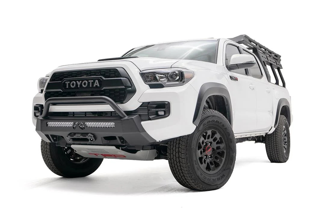 Fab Fours Hidden Winch Mount with low pre-runner guard on a white Toyota Tacoma, front three-quarter view, showing the low guard hoop, LED light bar, and winch fairlead