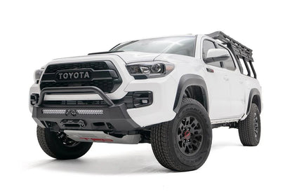 Fab Fours Hidden Winch Mount with low pre-runner guard on a white Toyota Tacoma, front three-quarter view, showing the low guard hoop, LED light bar, and winch fairlead