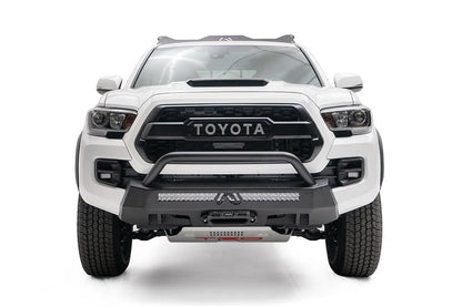 Fab Fours Hidden Winch Mount with low pre-runner guard on a white Toyota Tacoma, straight-on front view, showing the low guard hoop, LED light bar, and center fairlead