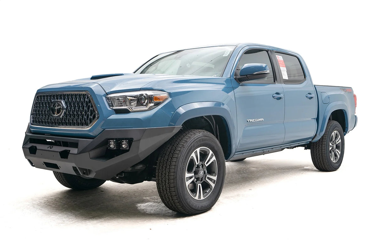 Fab Fours Matrix front bumper on a blue Toyota Tacoma, front three-quarter view, showing the no-guard design, cube light pods, and wraparound end caps
