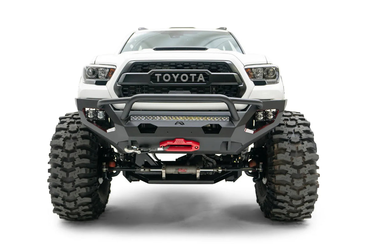 Fab Fours Matrix front bumper with pre-runner guard on a white Toyota Tacoma, straight-on front view, showing the pre-runner hoop, LED light bar, and center winch