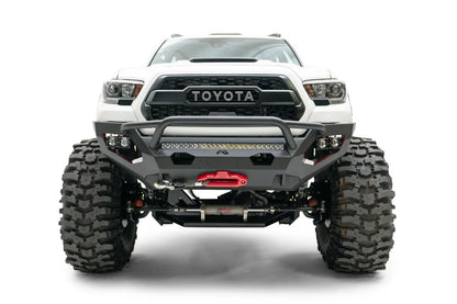 Fab Fours Matrix front bumper with pre-runner guard on a white Toyota Tacoma, straight-on front view, showing the pre-runner hoop, LED light bar, and center winch