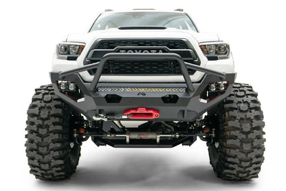 Fab Fours Matrix front bumper with pre-runner guard on a white Toyota Tacoma, straight-on front view, showing the pre-runner hoop, LED light bar, and center winch