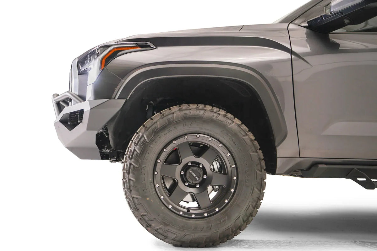 Fab Fours Vengeance front bumper with pre-runner guard on a gray Toyota Tundra, close-up side profile of the front corner, showing the bumper end cap, guard tubing, and wheel clearance