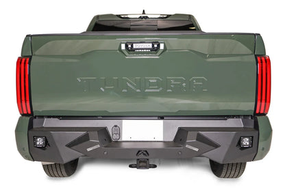 Fab Fours Vengeance rear bumper on a green Toyota Tundra, straight-on rear view, showing the full bumper width, cube light pods, and receiver hitch