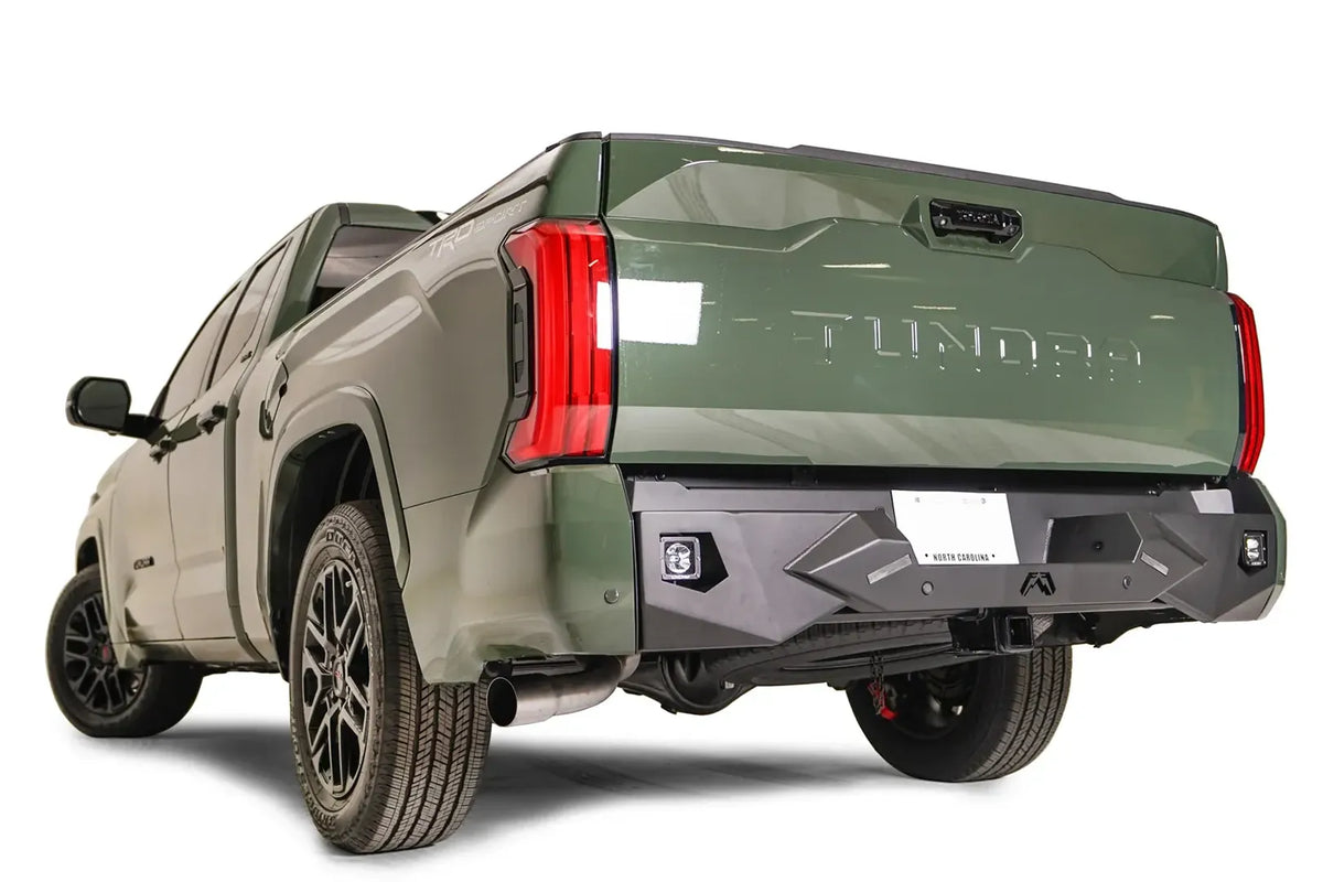 Fab Fours Vengeance rear bumper on a green Toyota Tundra, rear three-quarter view, showing the angular faceted face, cube light pods, and center plate mount
