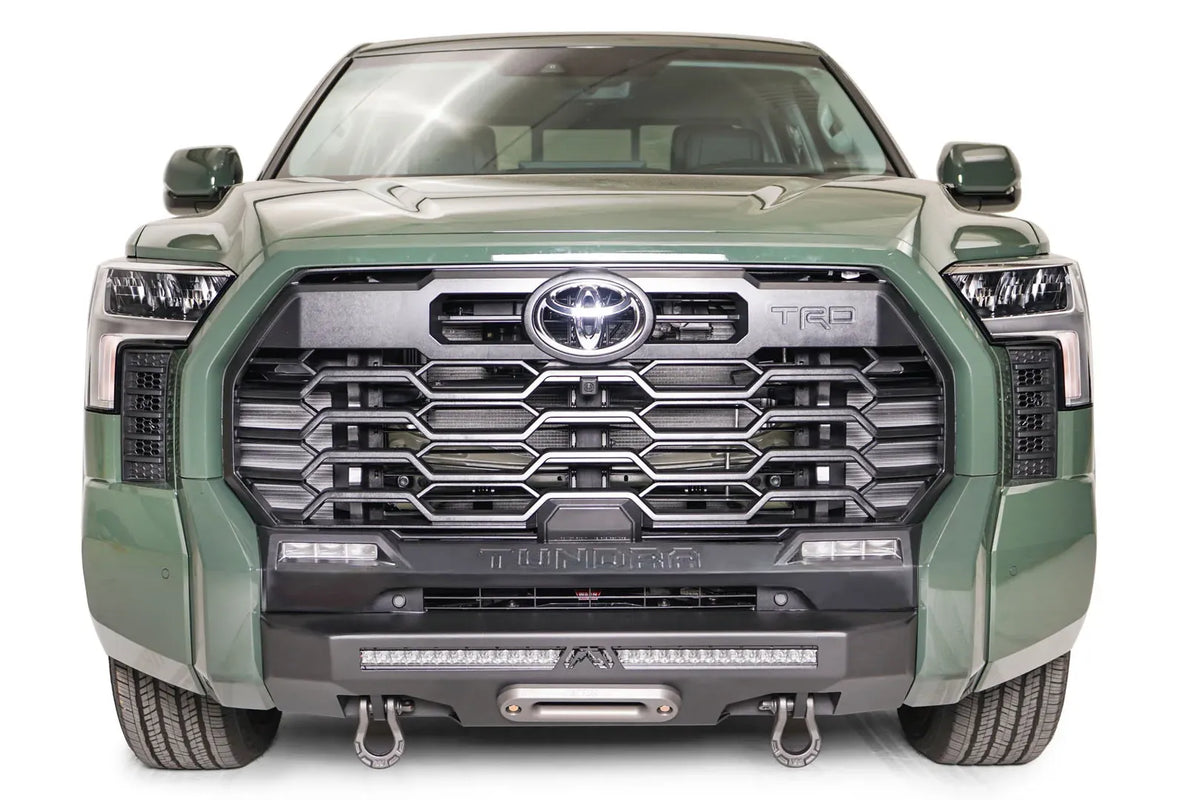 Fab Fours Hidden Winch Mount on a green Toyota Tundra, straight-on front view, showing the hidden winch fairlead, LED light bar, and D-ring shackles