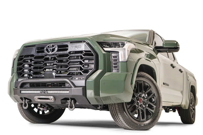 Fab Fours Hidden Winch Mount with pre-runner guard on a green Toyota Tundra, front three-quarter view, showing the guard hoop, winch fairlead, and D-ring shackles