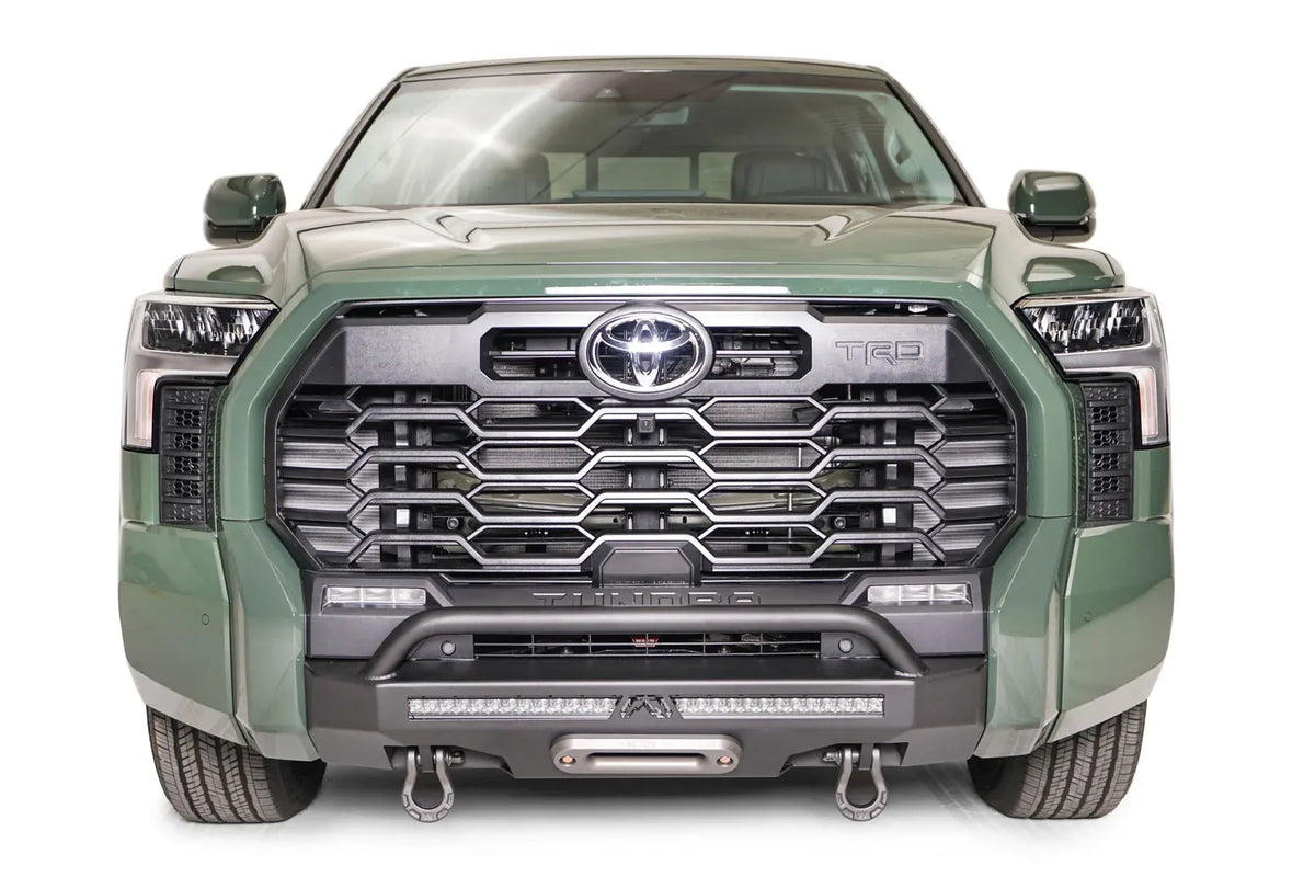 Fab Fours Hidden Winch Mount with pre-runner guard on a green Toyota Tundra, straight-on front view, showing the guard hoop, LED light bar, and D-ring shackles