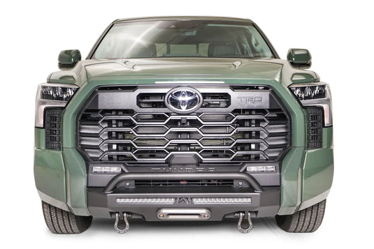 Fab Fours Hidden Winch Mount with pre-runner guard on a green Toyota Tundra, straight-on front view, showing the guard hoop, LED light bar, and D-ring shackles