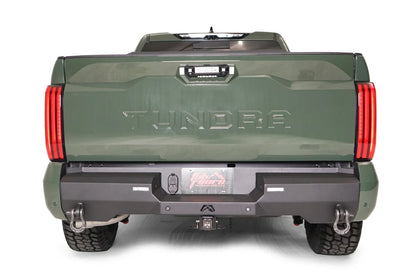 Fab Fours Premium rear bumper on a green Toyota Tundra, straight-on rear view, showing the full bumper width, D-ring shackles, and receiver hitch