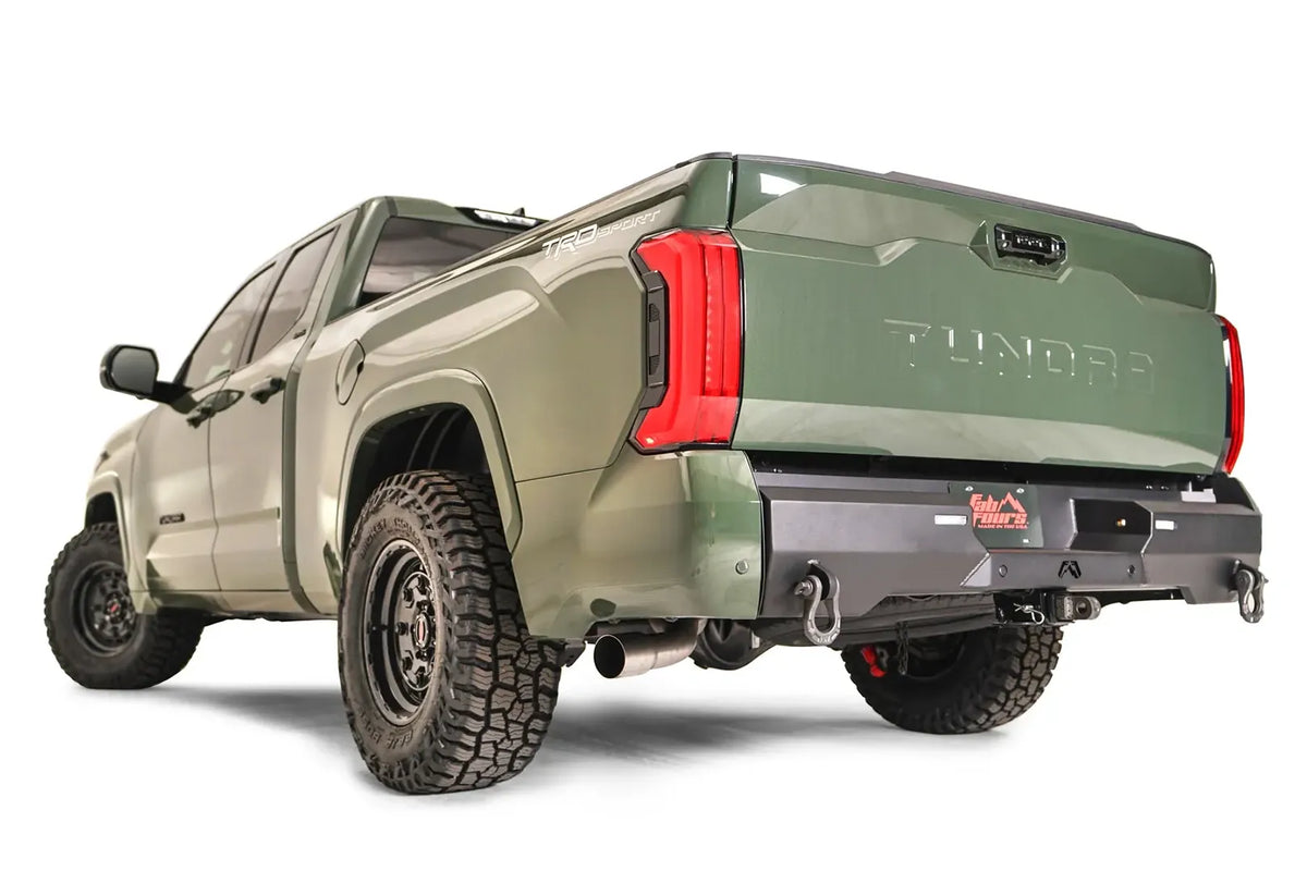 Fab Fours Premium rear bumper on a green Toyota Tundra, rear three-quarter view, showing the recessed light pods, D-ring shackle mounts, and center plate mount