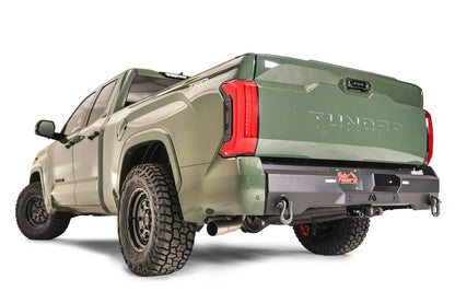 Fab Fours Premium rear bumper on a green Toyota Tundra, rear three-quarter view, showing the recessed light pods, D-ring shackle mounts, and center plate mount