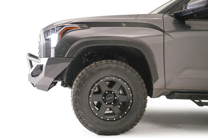 Fab Fours Matrix front bumper with pre-runner guard on a gray Toyota Tundra, close-up side profile of the front corner, showing the bumper end cap, guard tubing, and wheel clearance