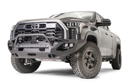 Fab Fours Matrix front bumper with pre-runner guard on a gray Toyota Tundra, front three-quarter view, showing the pre-runner hoop, cube light pods, and winch fairlead