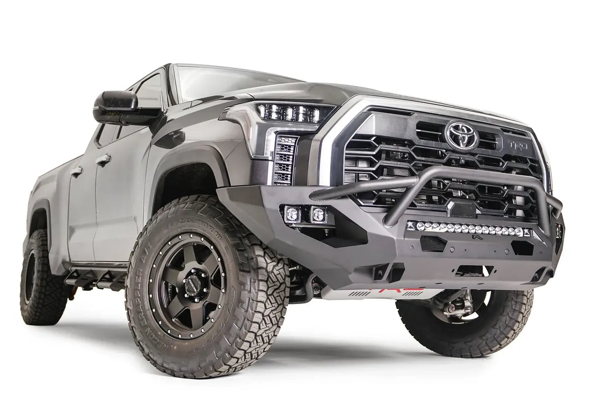 Fab Fours Matrix front bumper with pre-runner guard on a gray Toyota Tundra, front three-quarter view, showing the pre-runner hoop, LED light bar, and cube light pods
