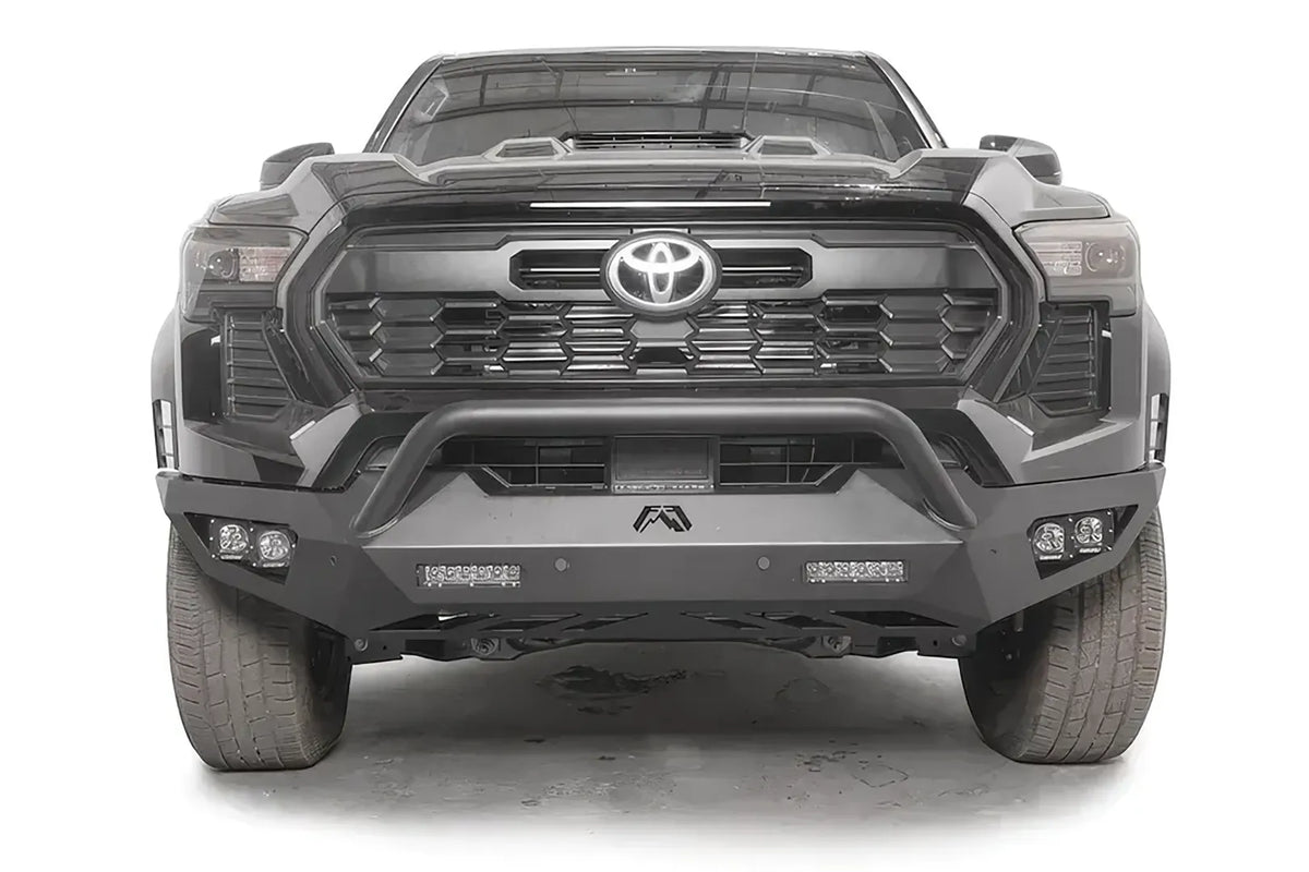 Fab Fours Vengeance front bumper with pre-runner guard on a dark gray Toyota Tacoma, straight-on front view, showing the pre-runner hoop, LED light bars, and cube light pods