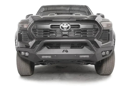 Fab Fours Vengeance front bumper with pre-runner guard on a dark gray Toyota Tacoma, straight-on front view, showing the pre-runner hoop, LED light bars, and cube light pods