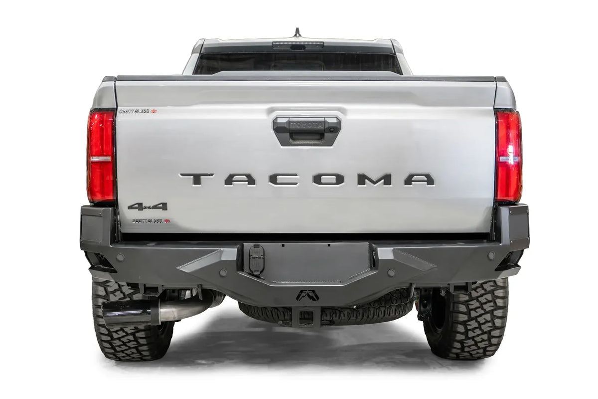 Fab Fours Vengeance rear bumper on a silver Toyota Tacoma, straight-on rear view, showing the full bumper width, center plate mount, and sensor-ready face