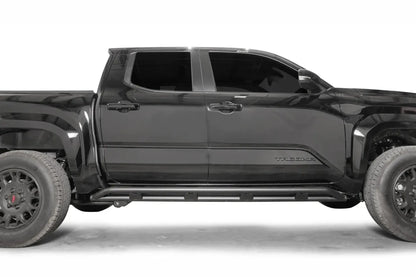 Fab Fours tube rock slider on a black Toyota Tacoma, passenger-side profile, showing the slider running