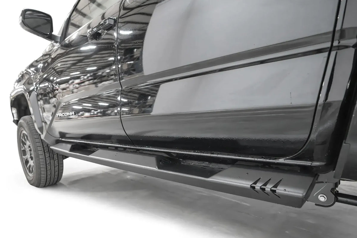 Close-up of the Fab Fours step slider on a black Toyota Tacoma, driver side