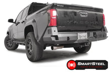 Fab Fours Premium rear sensor bumper on a dark gray Toyota Tacoma, rear three-quarter view, showing the angled end cap, recessed light, and center plate mount