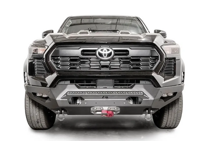 Fab Fours Matrix front bumper on a dark gray Toyota Tacoma, straight-on front view, showing the full-width bumper, LED light bar, and center winch