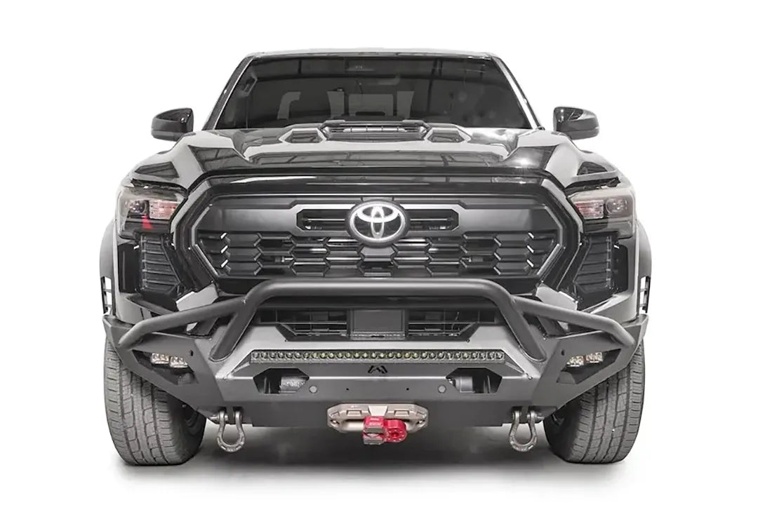 Fab Fours Matrix front bumper with pre-runner guard on a black Toyota Tacoma, straight-on front view, showing the pre-runner hoop, LED light bar, and center winch