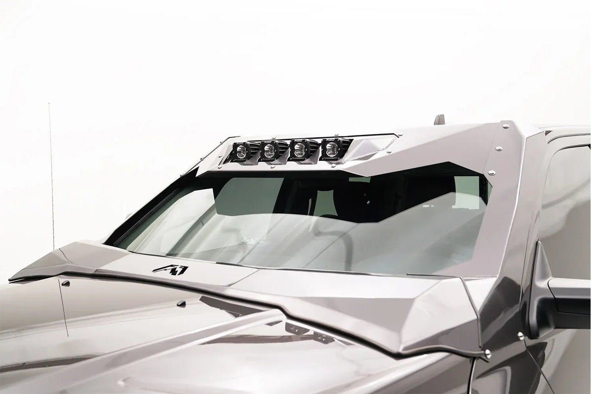 Fab Fours ViCowl on a silver Ram 2500, close-up of the windshield area, showing the black powder-coated frame cover, four light pods, and A-pillar wrap
