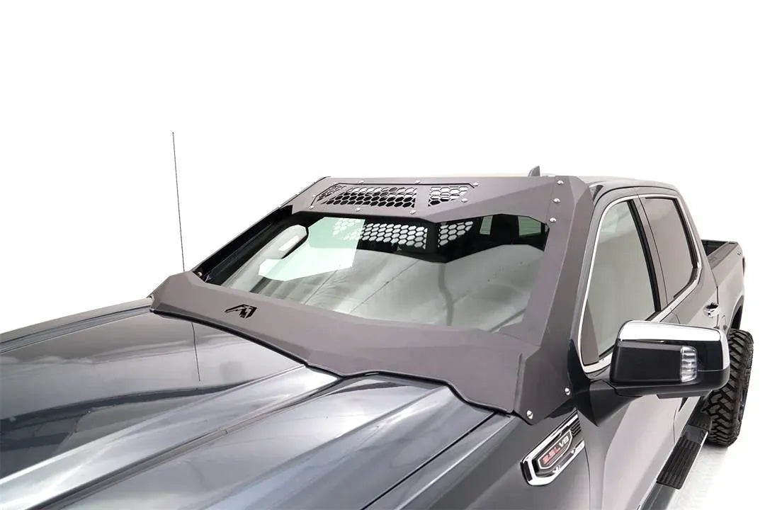 Close-up of the Fab Fours ViCowl on a gray GMC Sierra 1500, driver side, showing the steel A-pillar cover, honeycomb top panels and bolted cowl wrapping the windshield