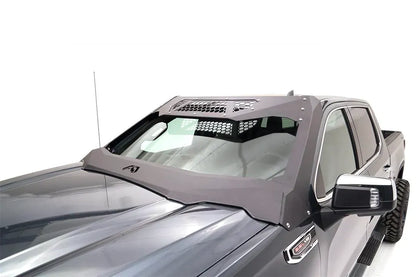 Close-up of the Fab Fours ViCowl on a gray GMC Sierra 1500, driver side, showing the steel A-pillar cover, honeycomb top panels and bolted cowl wrapping the windshield