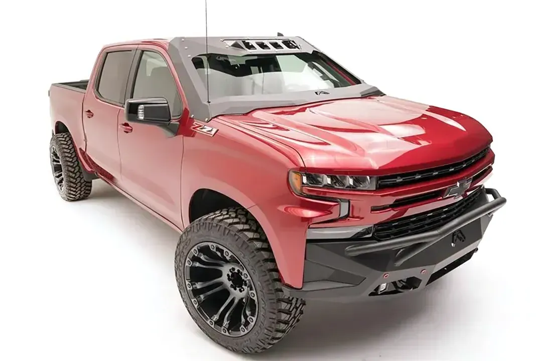 Fab Fours ViCowl on a red Chevrolet Silverado 1500, front three-quarter view, showing the windshield frame cover, light pods, and A-pillar wrap
