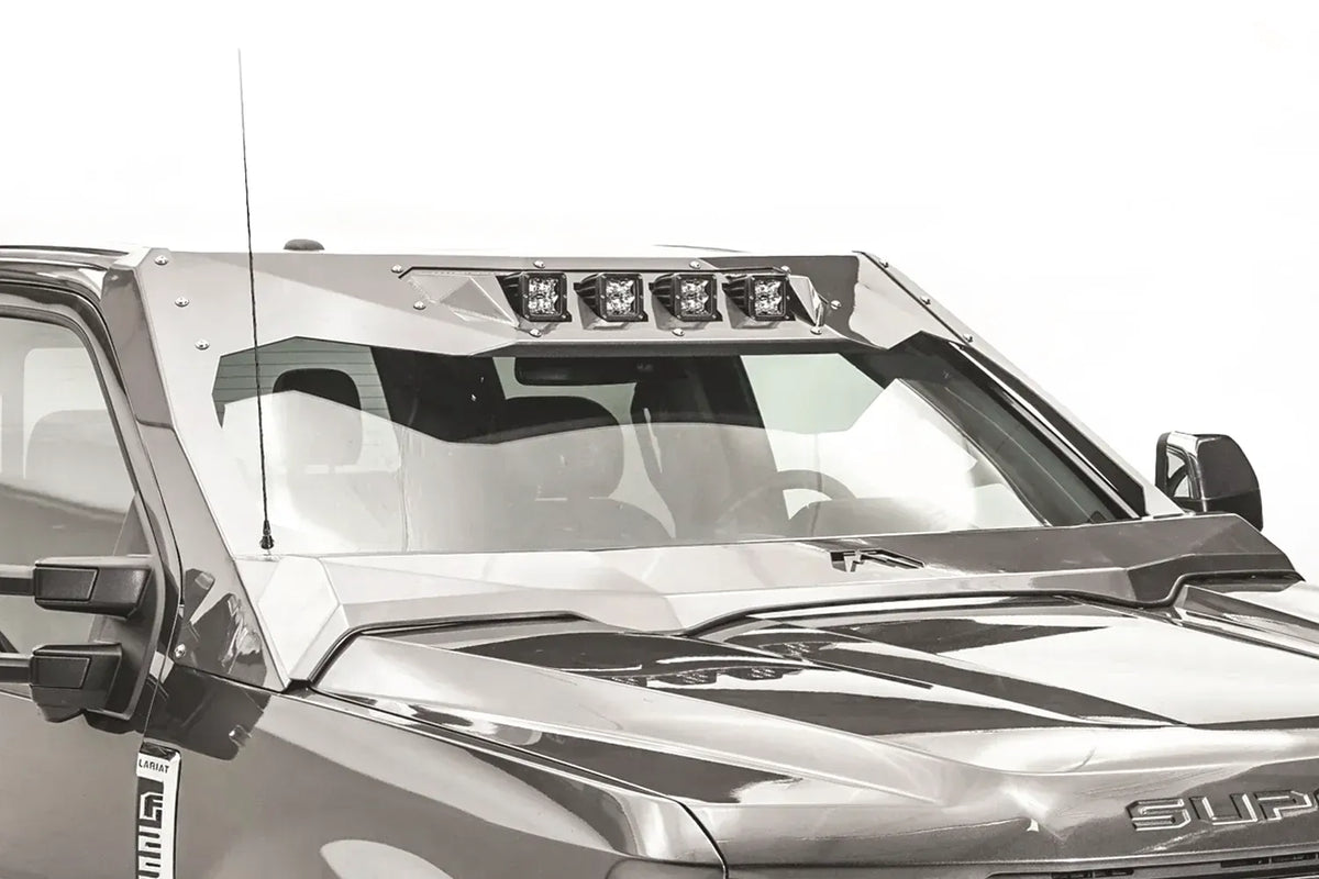 Close-up of the Fab Fours ViCowl on a Ford Super Duty, showing four cube lights in the top light bar, steel A-pillar covers and the Fab Fours logo on the cowl over the hood
