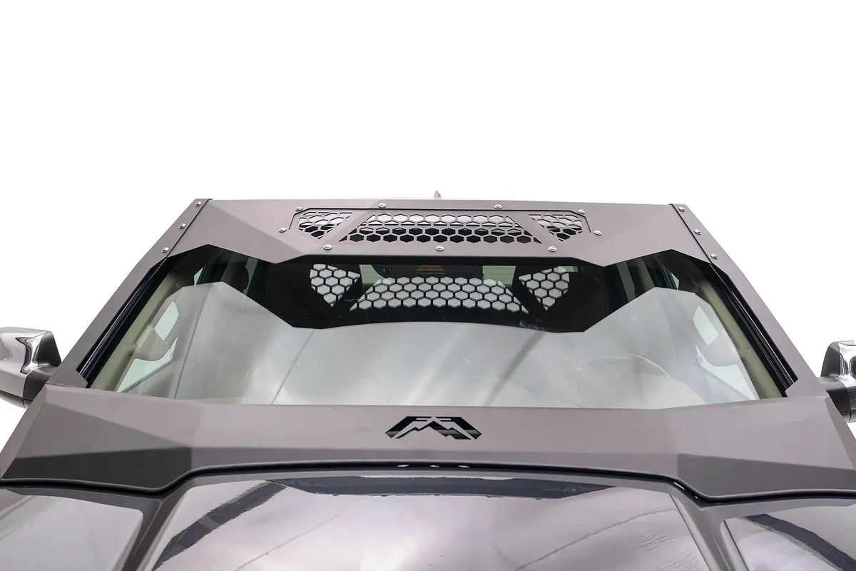 Fab Fours ViCowl on a Ram 1500, elevated front view over the hood, showing the angular steel cowl, honeycomb mesh visor panels and Fab Fours logo at the base of the windshield