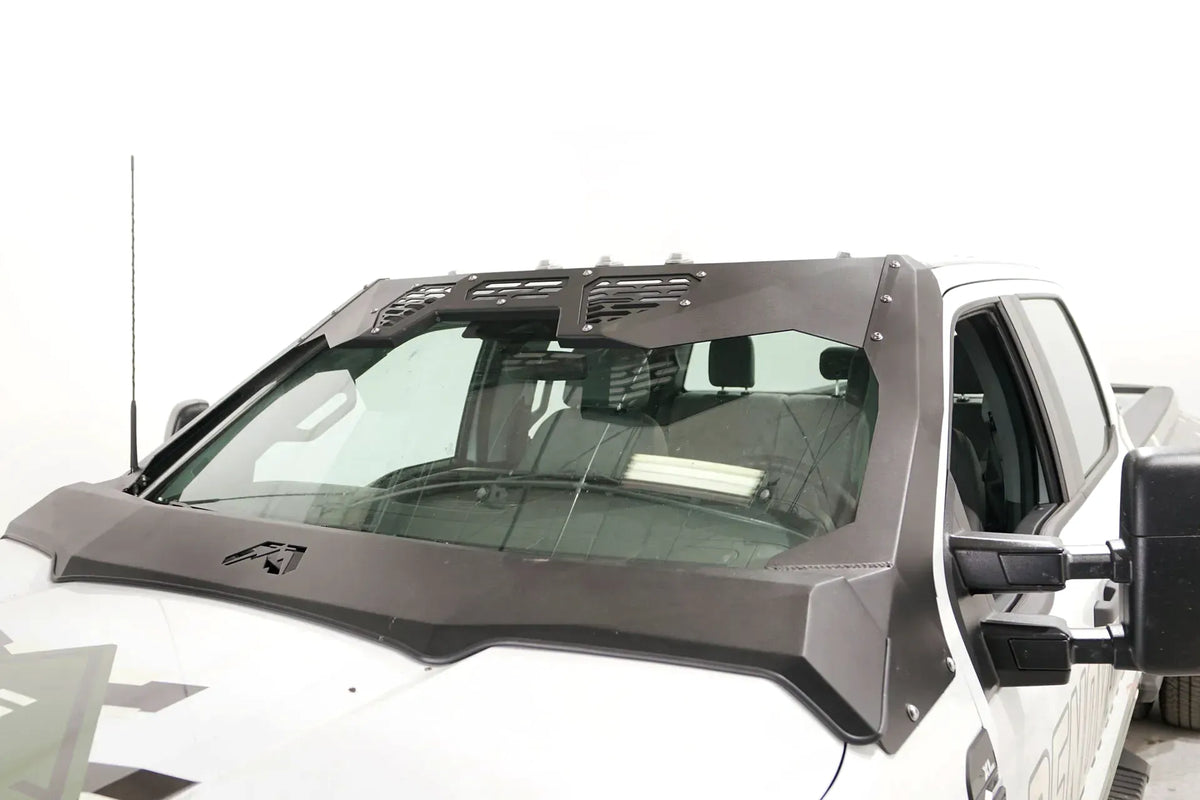 Fab Fours ViCowl Windshield Protection on a white Ford Super Duty, angled driver-side view, showing the matte black steel cowl with vented light pod panels, A-pillar covers and Fab Fours logo