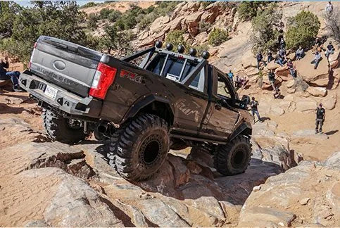 Fab Fours Daylighter Ford Super Duty navigating a Moab trail obstacle during Easter Jeep Safari