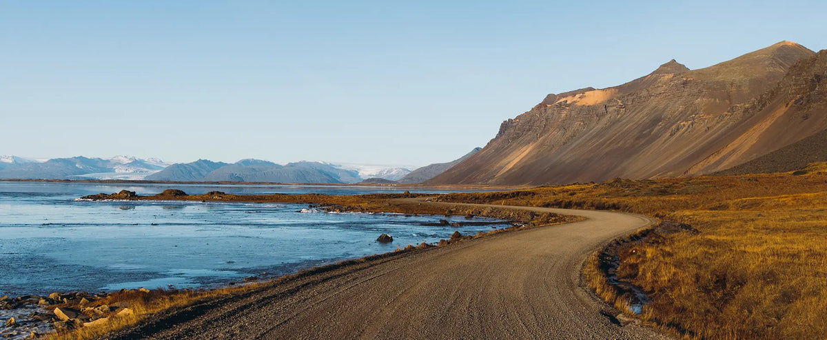 Winding coastal road along a mountain lakeshore at sunset