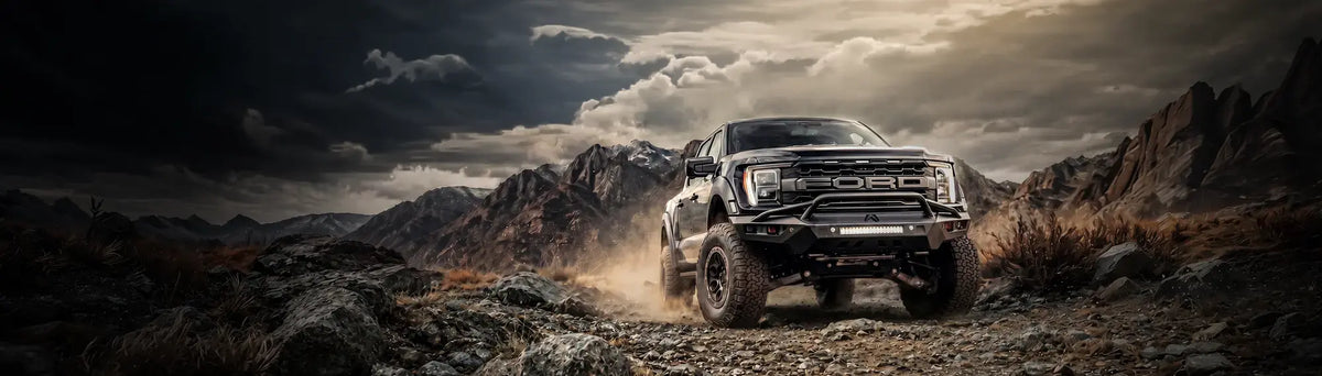 Truck with Fab Fours Vengeance front bumper on off-road terrain at dusk